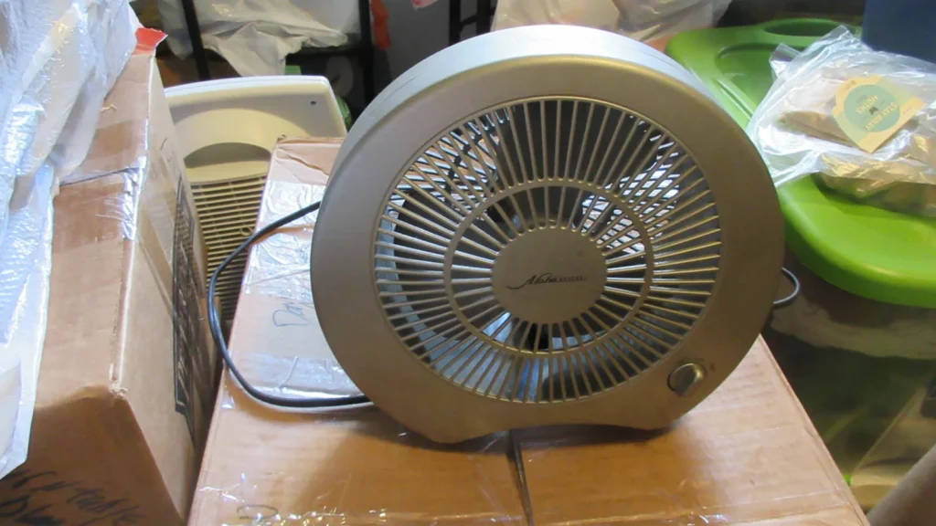 Ventilador pequeño de sobremesa funcionando sobre una caja