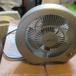 Ventilador pequeño de sobremesa funcionando sobre una caja