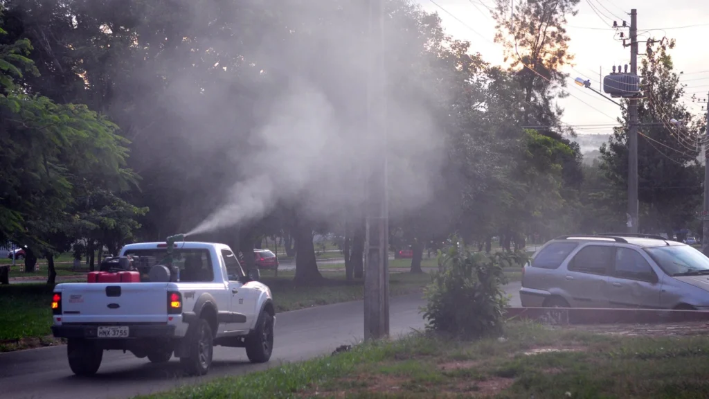 Fumigar moscas: cómo se hace y qué producto sirve 1 Trabajador con equipo de nebulización aplicando insecticida en la calle, con una nube de niebla sobre la vía pública